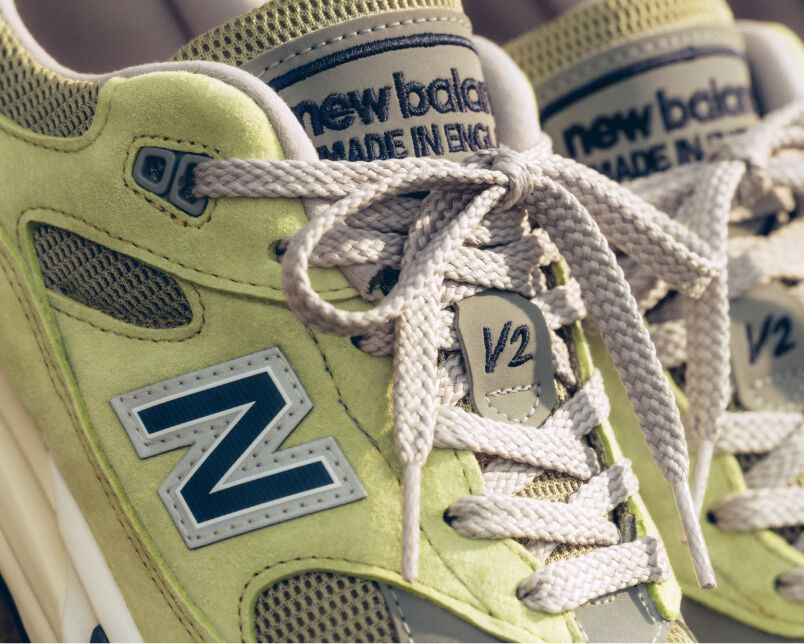A pair of New Balance Made in UK sneakers in front of a rabbit in a brown textured studio environment. 