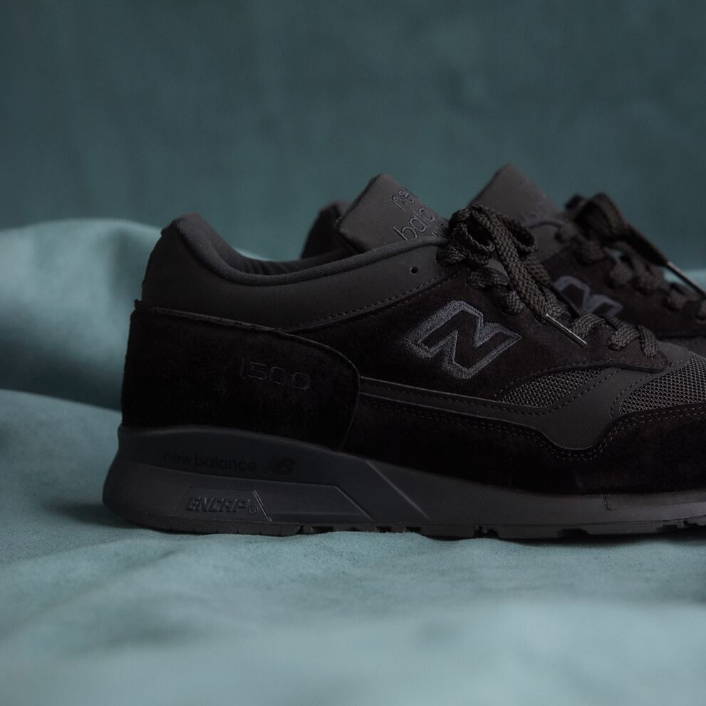 A close up view of the heel of a New Balance Made in UK sneaker on a flowing blue sheet backdrop.