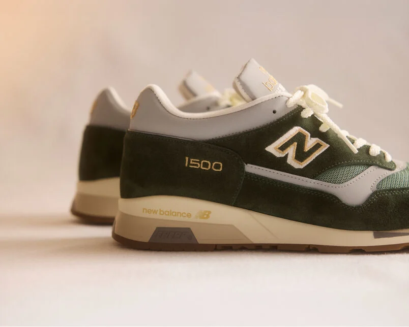 A pair of New Balance Made in UK sneakers on a green textured studio environment. 
