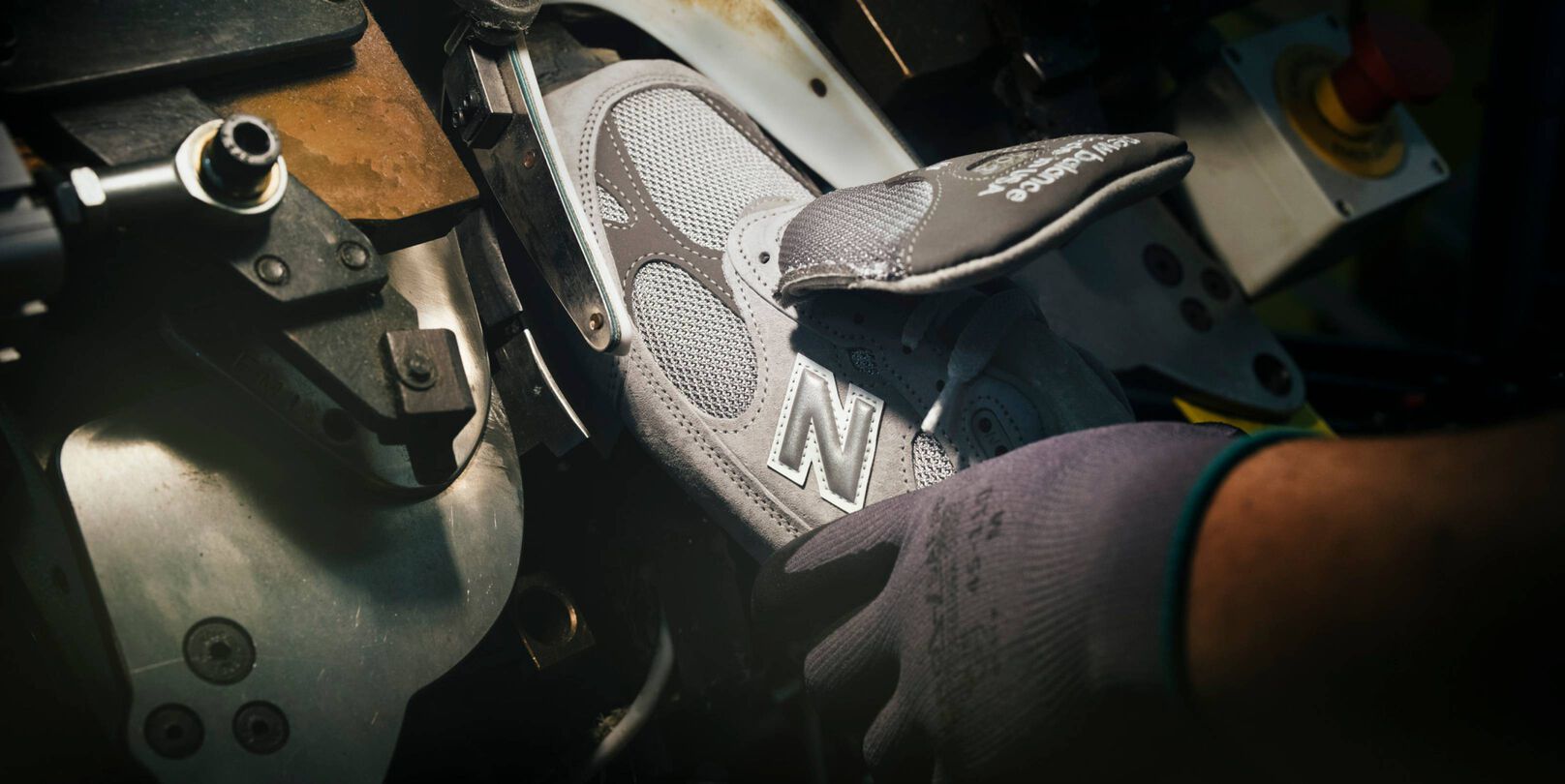 A hand putting a sneaker into a machine during its construction.