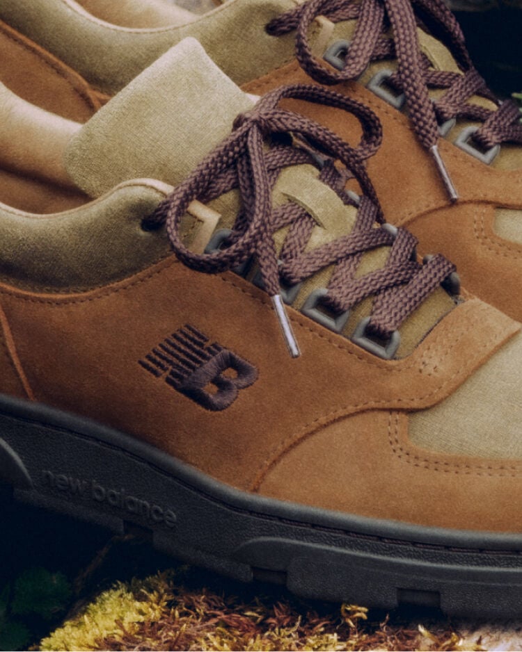 Detailed view of a pair of New Balance Made in UK sneakers sitting on a moss covered rock. 